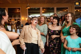   At Garvan's in New Paltz, New York, the mother of the bride laughs wholeheartedly as an unexpected piece of cake ends up on her face during the lively cake-cutting festivities.